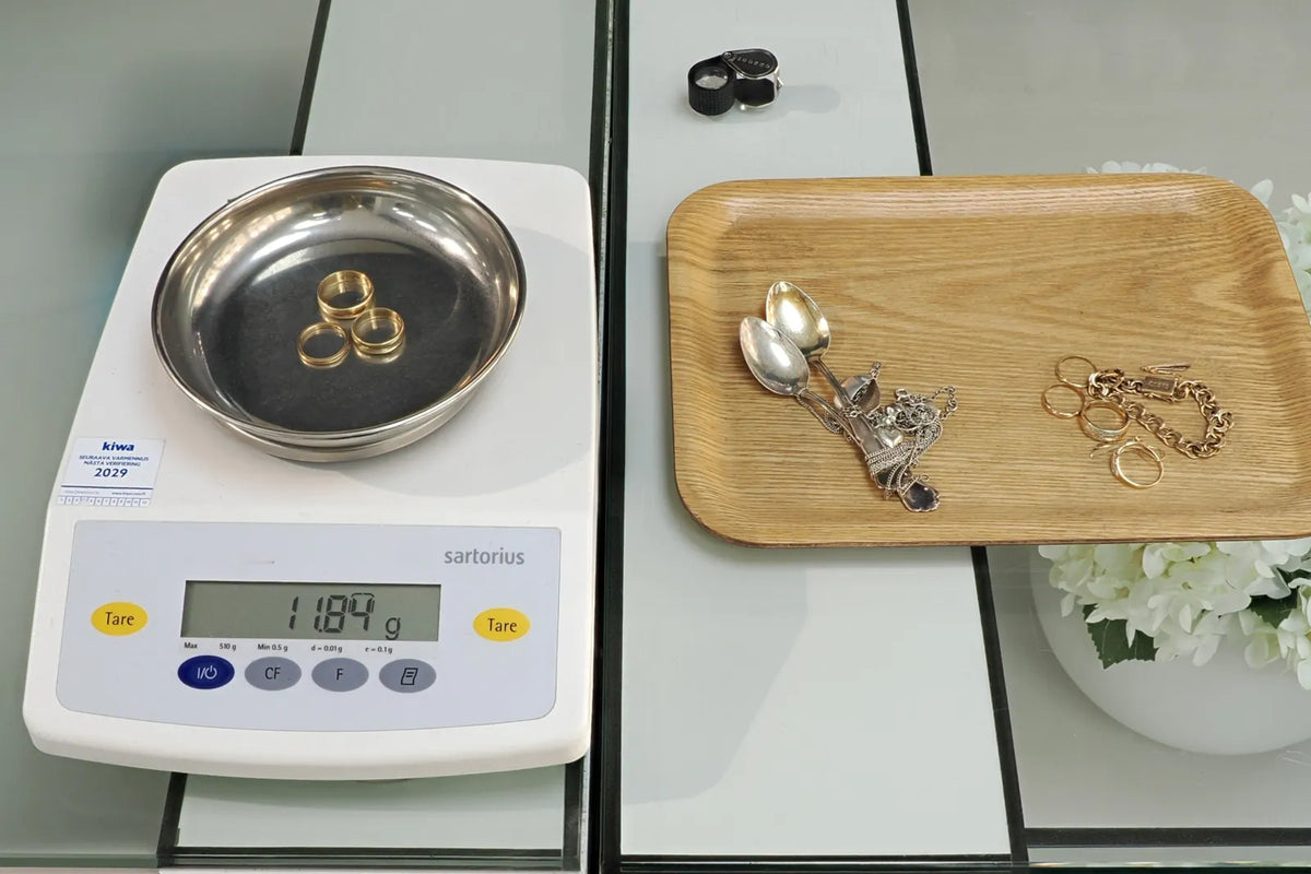 Kolme kultasormusta tarkkuusvaa'alla, lukema 11,84 g; vieressä alustalla hopeat ja kullat omina ryhminään.